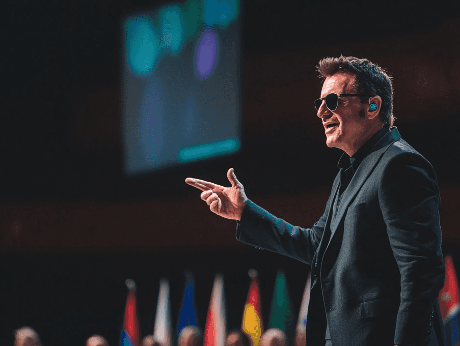 Bono speaking passionately at a global summit, addressing world leaders and activists