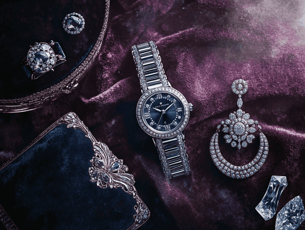 A flat lay of luxury accessories, including a Van Cleef & Arpels secret watch, diamond earrings, and a velvet clutch